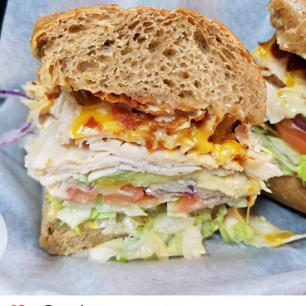 A large, sliced turkey sandwich on whole wheat bread with cheese, lettuce, and tomatoes.